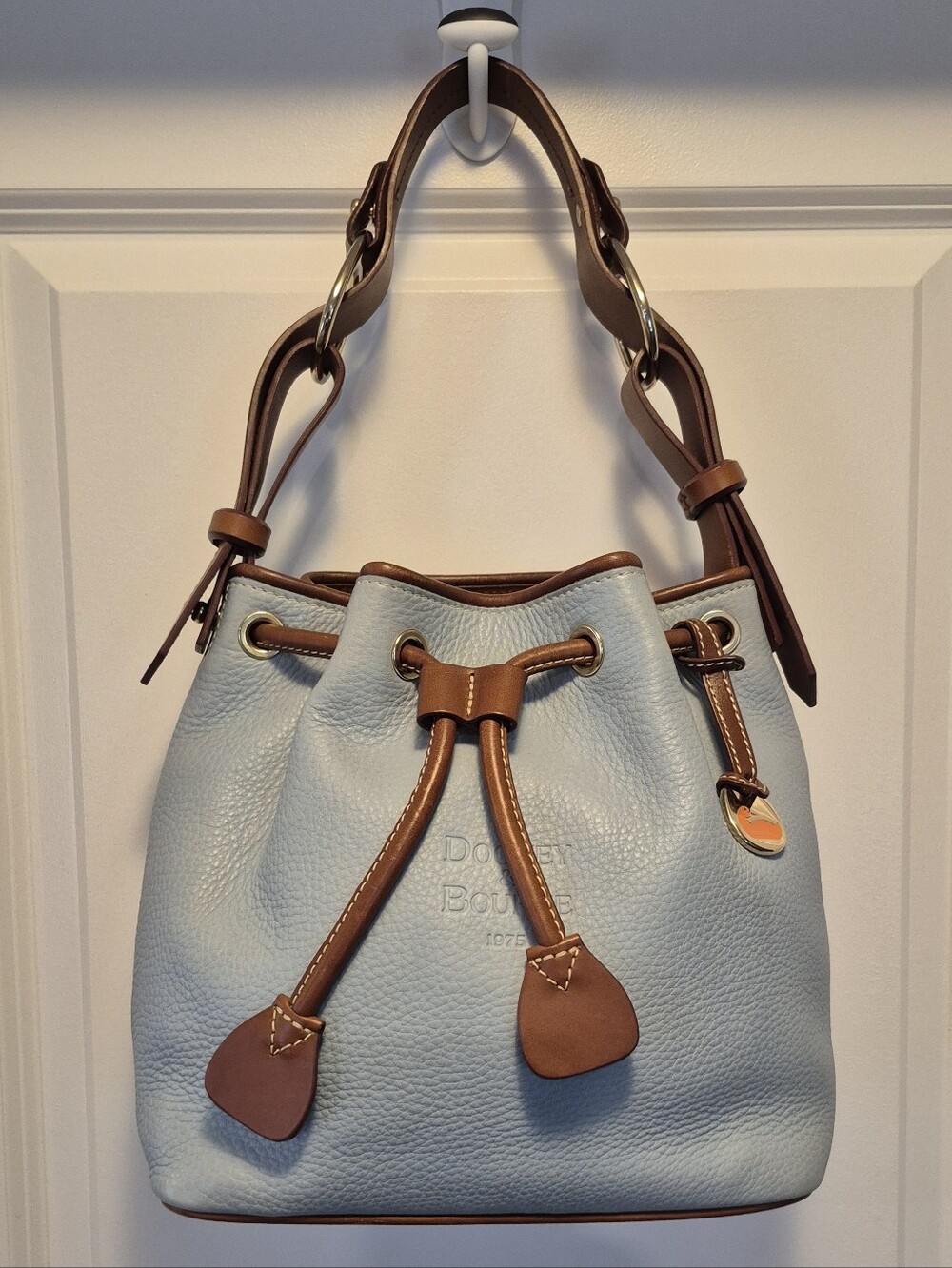 Dooney & Bourke Light Blue Pebble Leather Drawstring Bucket Bag with Brown Trim.